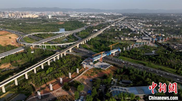 航拍正在建設的跨越成都繞城高速公路連續(xù)梁施工現(xiàn)場，旁邊依次為已運營的成渝高速鐵路和機場高速公路?！⒅铱?攝