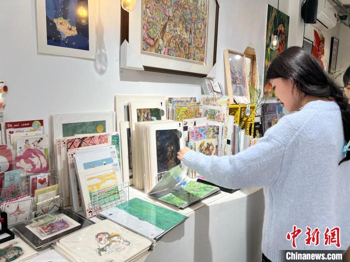 圖為藝術(shù)品商店內(nèi)，顧客挑選插畫(huà)作品?！＄婌?攝
