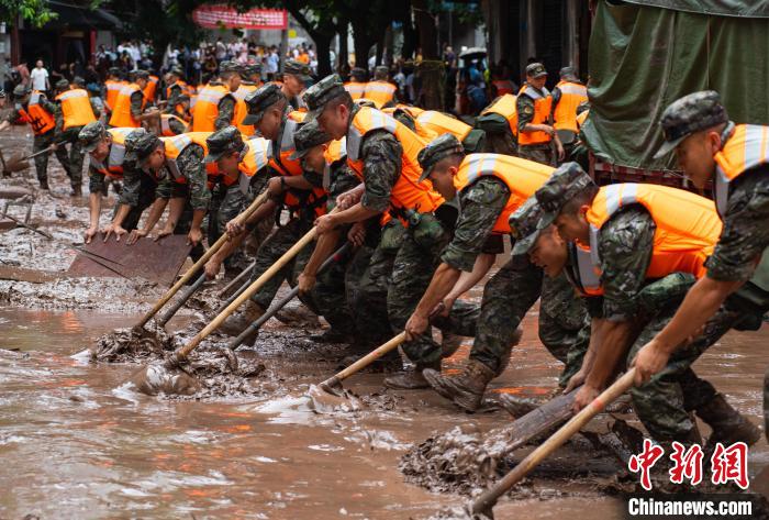 7月4日，萬(wàn)州區(qū)五橋街道，武警官兵清理街道上的淤泥。　冉孟軍 攝