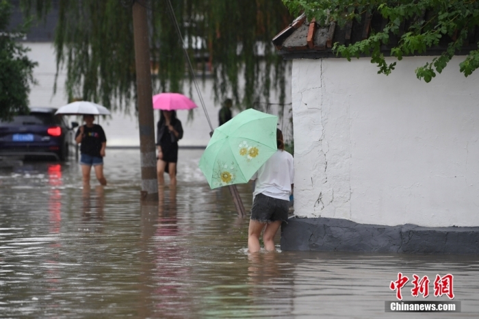 7月31日，市民行走在雨中的北京房山區(qū)瓦窯頭村。北京市氣象臺當(dāng)日10時發(fā)布分區(qū)域暴雨紅色預(yù)警信號。北京市水文總站發(fā)布洪水紅色預(yù)警，預(yù)計當(dāng)日12時至14時，房山區(qū)大石河流域?qū)⒊霈F(xiàn)紅色預(yù)警標(biāo)準(zhǔn)洪水。<a target='_blank' href='/'><p  align=
