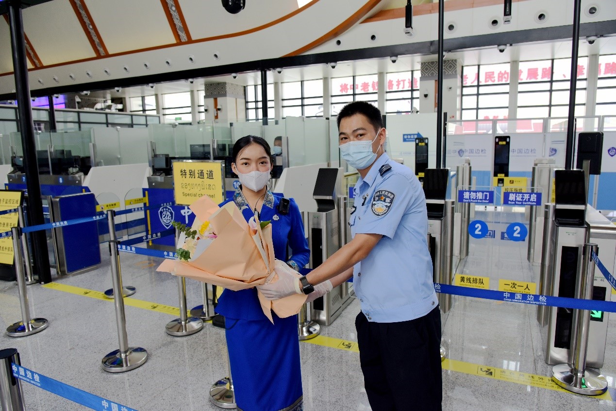 磨憨出入境邊防檢查站民警為中老鐵路第100萬名出入境旅客，D888次國(guó)際旅客列車?yán)蠐爰藙?wù)員森達(dá)拉·妮緹婭（Sengdala Nitiya），送上鮮花。黃遠(yuǎn)飛 攝