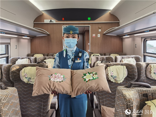 趙瑩靜展示中老鐵路國際旅客列車里帶有中國牡丹花和老撾占巴花刺繡圖案的靠墊。人民網(wǎng)記者 杜明明攝
