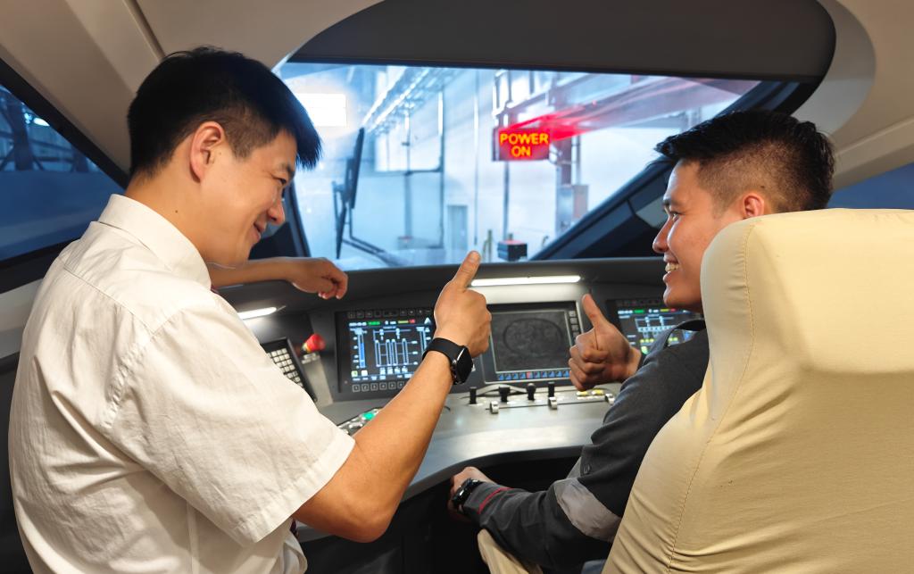 8月25日，在印度尼西亞萬隆的雅萬高鐵德卡魯爾動車所內(nèi)，中國師傅穆振（左）在向印尼火車司機(jī)塞蒂亞萬講解動車組出庫前的上電作業(yè)。