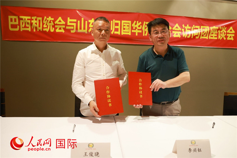 中國僑聯(lián)副主席、山東省僑聯(lián)主席李興鈺（右）與巴西和統(tǒng)會會長王俊曉簽署合作協(xié)議書。人民網(wǎng)記者 陳海琪攝