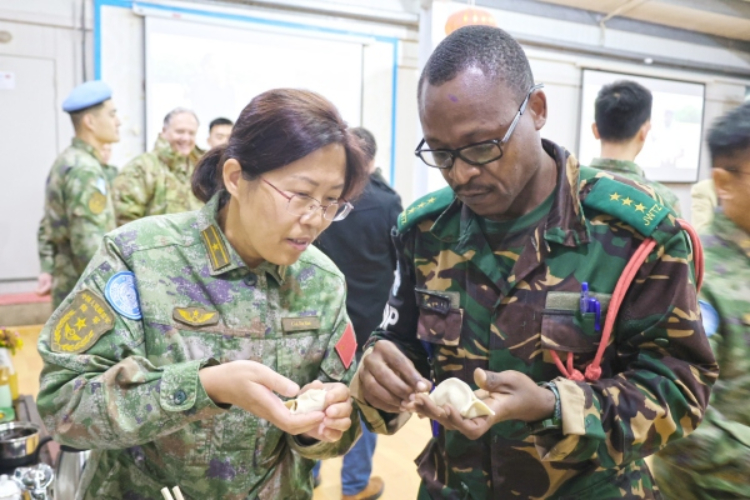圖為維和官兵與外軍人員共同包餃子。胡光明攝