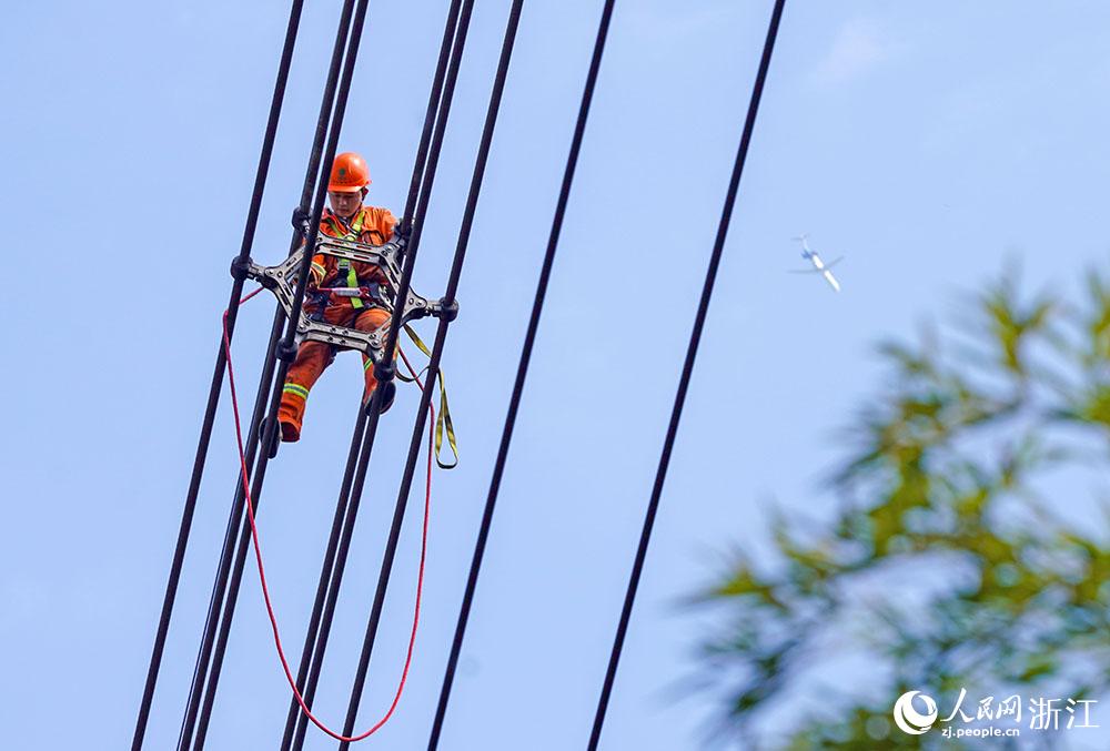 3月11日，在浙江省諸暨市河上鎮(zhèn)，浙江省送變電工程有限公司檢修人員在高空的導(dǎo)線上進(jìn)行線路檢修維護(hù)。人民網(wǎng) 章勇濤攝