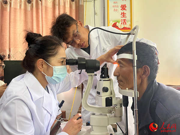 王紅英（左）和團(tuán)隊(duì)成員為達(dá)熱村村民檢查眼睛。人民網(wǎng)記者 杜燕飛攝