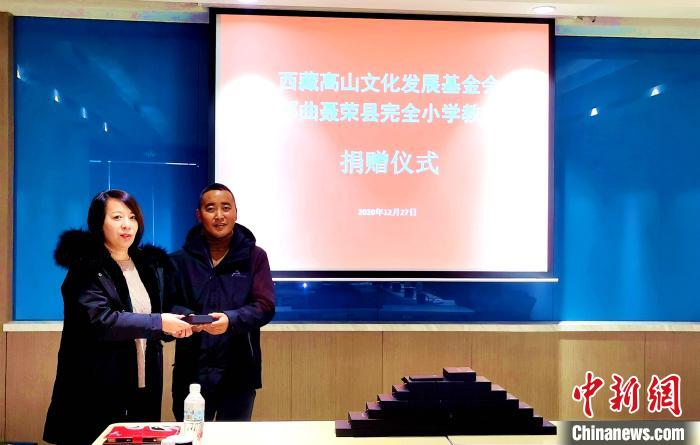 圖為西藏高山文化發(fā)展基金會(huì)理事長(zhǎng)溫麗向聶榮縣完全小學(xué)負(fù)責(zé)人捐助儀器?！∮谫e 攝