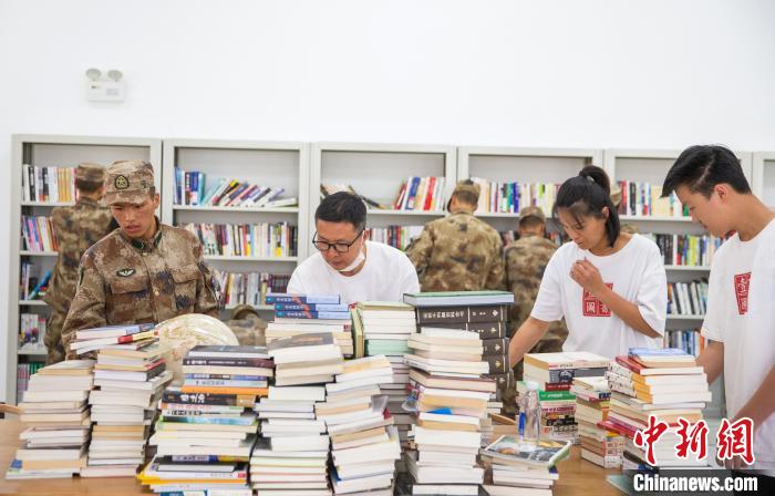 圖為志愿者們和邊防戰(zhàn)士整理圖書?！詵| 攝