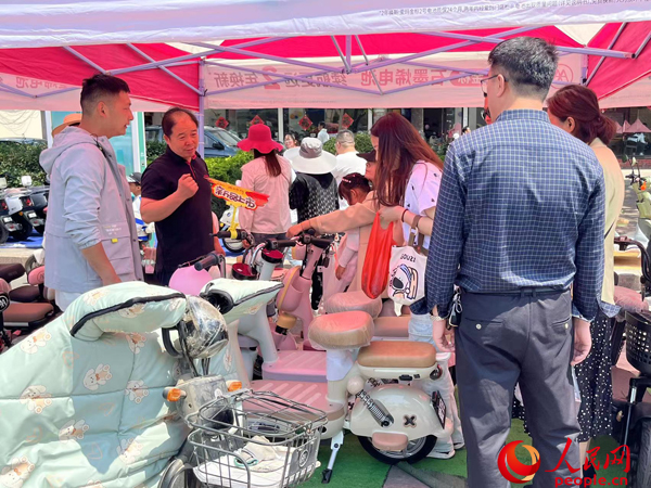 某電動(dòng)自行車品牌工作人員向消費(fèi)者介紹以舊換新相關(guān)情況。人民網(wǎng)記者 杜燕飛攝