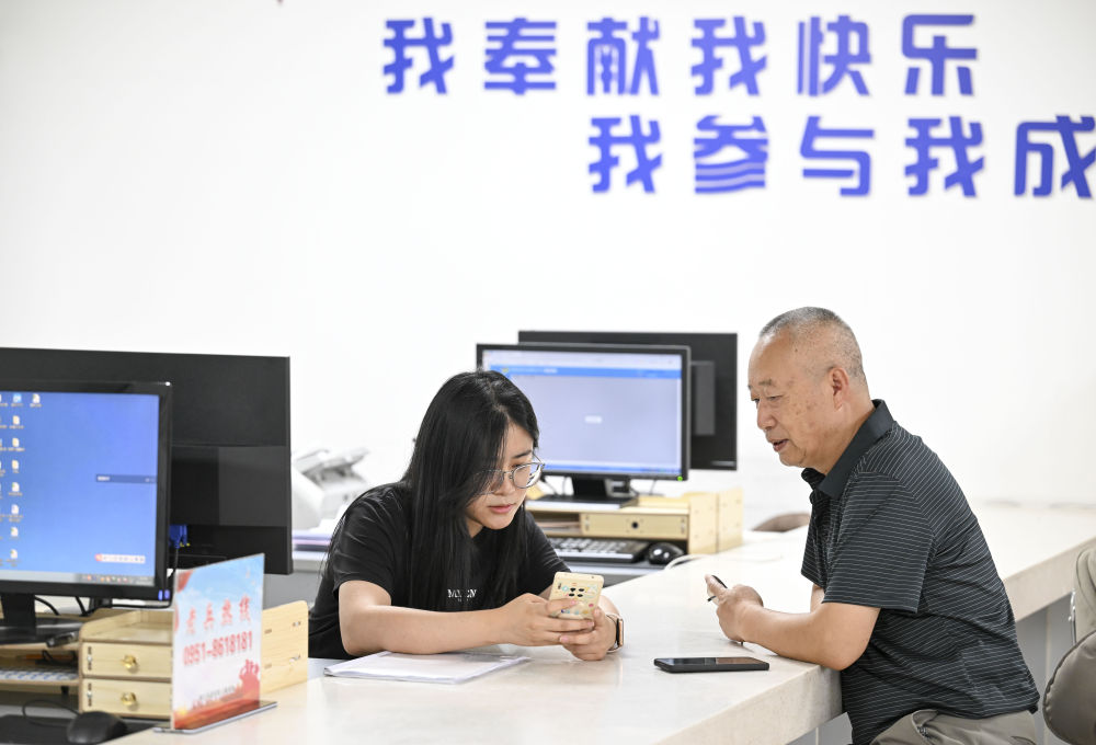 2024年6月20日，在寧夏銀川市金鳳區(qū)長城花園社區(qū)黨群服務(wù)中心，工作人員幫助居民辦理業(yè)務(wù)。圖片來源 新華社