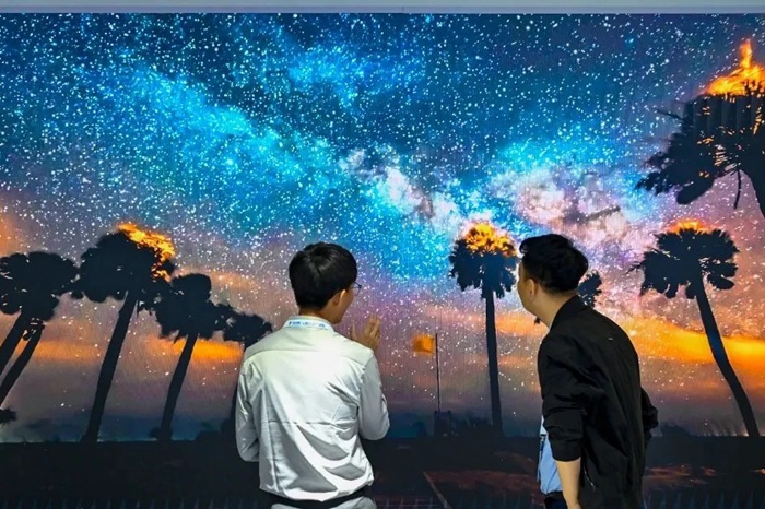 長春光博會希達電子展區(qū)，一位工作人員正在給一位觀眾講解。（長春新區(qū)供圖）