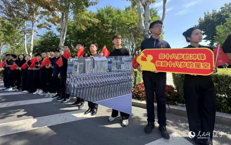 沈陽市人民廣場上，大學(xué)生們手持閱兵的圖片，告慰英烈。人民網(wǎng)記者 周頌雪攝