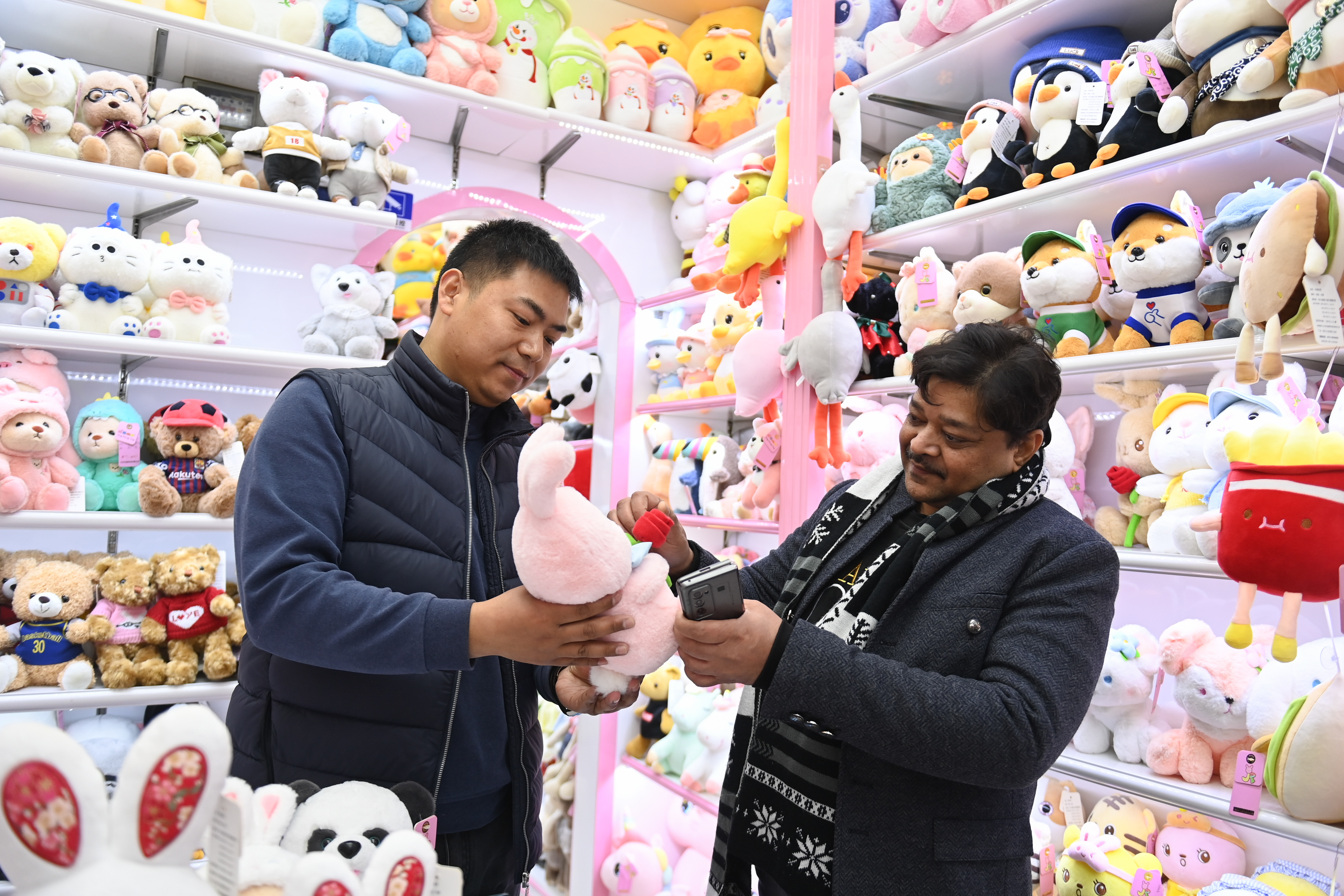 2023年2月2日，來自印度的客商（右）在義烏國際商貿(mào)城的一家玩具店鋪內(nèi)選購。