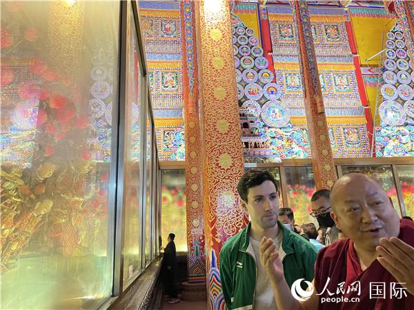7月25日，省級非物質(zhì)文化遺產(chǎn)項(xiàng)目塔爾寺酥油花的代表性傳承人朋措堅(jiān)參（右）在塔爾寺酥油花館講解酥油花的制作過程。人民網(wǎng) 謝瑩攝