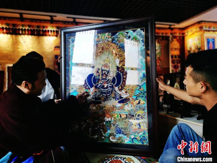 圖為久美尖措(左)與徒弟們展示唐卡作品?！?zhí)砀?攝