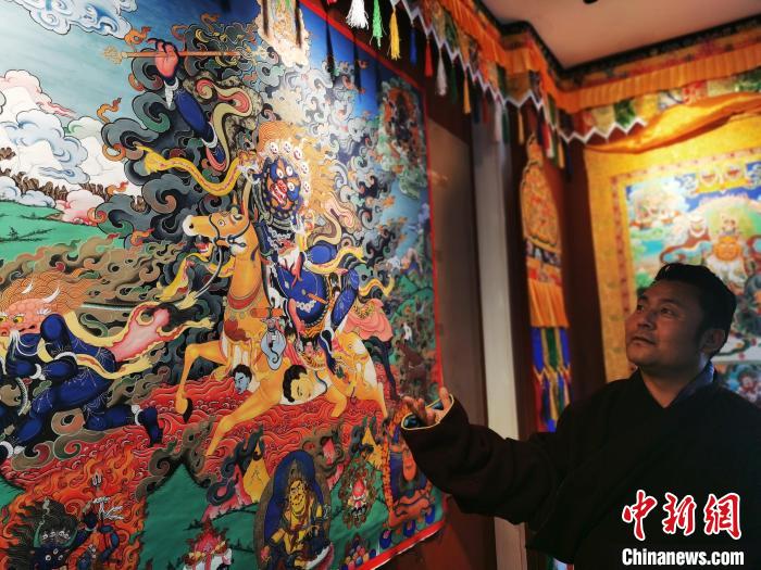 圖為久美尖措展示唐卡作品?！?zhí)砀?攝