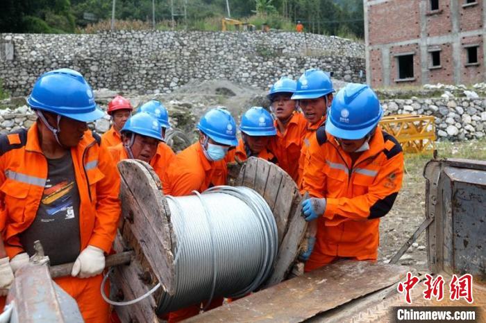 國網(wǎng)四川送變電公司搶險隊員將重達370公斤的鋼絞線搬上車?！⑾驸C 攝