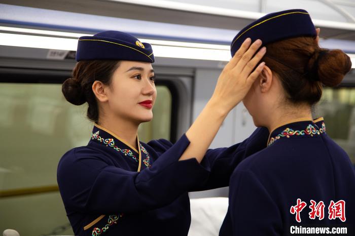 圖為青藏鐵路西格段“復(fù)興號”動車組乘務(wù)員互相整理新制服?！±罾?攝