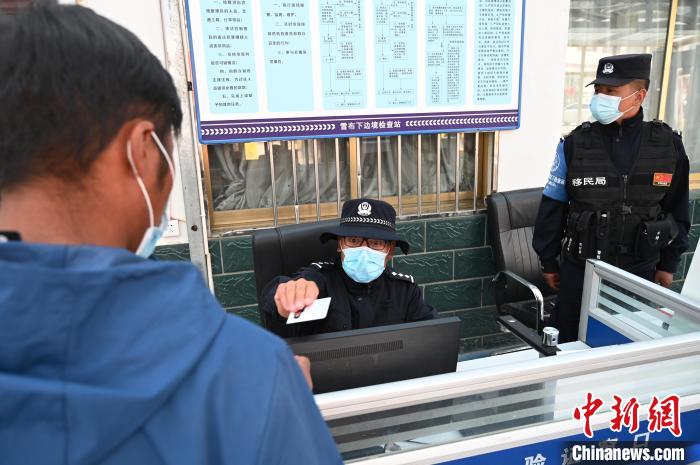 圖為移民管理警察登記完身份信息后將證件歸還給行人?！≮w朗 攝