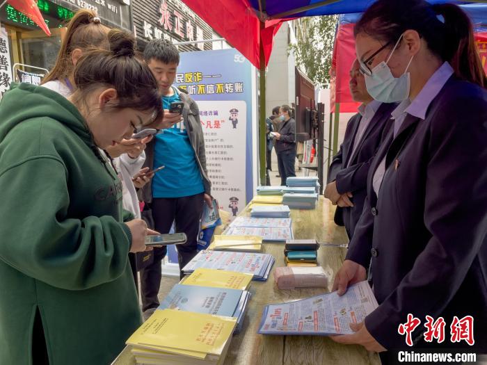 圖為工作人員正在向路過市民介紹國家反詐中心軟件的功能?！≈x牧 攝
