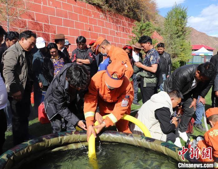 圖為森林消防員為護(hù)林員講解滅火裝備的使用方法?！〔际猩窒乐ш?duì) 供圖