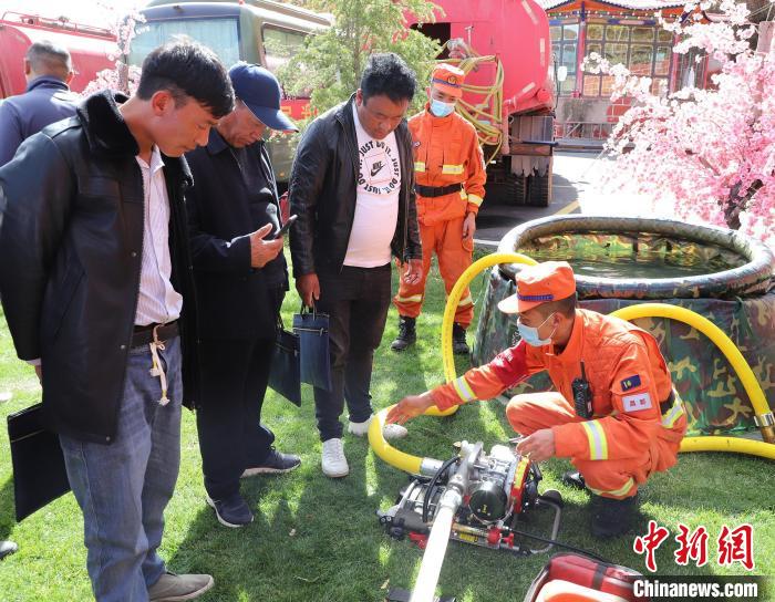 圖為森林消防員為護(hù)林員講解滅火裝備的使用方法?！〔际猩窒乐ш?duì) 供圖