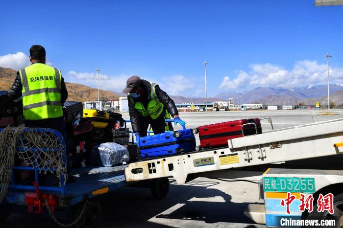 圖為機(jī)場工作人員傳送旅客行李箱。　周航 攝