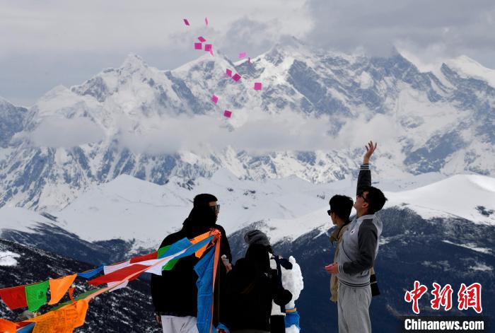 圖為5月14日，游客在西藏林芝色季拉山觀景臺拋灑“隆達(dá)”(風(fēng)馬旗，藏族民眾的一種祈福方式)?！±盍?攝
