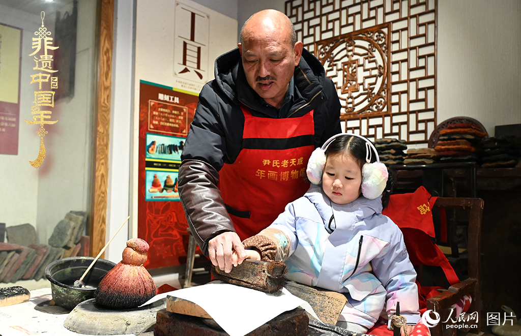 2025年1月27日，河南開封朱仙鎮(zhèn)木版年畫藝人尹國法指導(dǎo)小朋友研習(xí)年畫印制技藝。朱仙鎮(zhèn)木版年畫源自漢唐壁畫藝術(shù)，是中國木版年畫的鼻祖。2006年5月20日，朱仙鎮(zhèn)木版年畫經(jīng)國務(wù)院批準(zhǔn)列入第一批國家級非物質(zhì)文化遺產(chǎn)名錄。人民網(wǎng)記者 王玉興攝